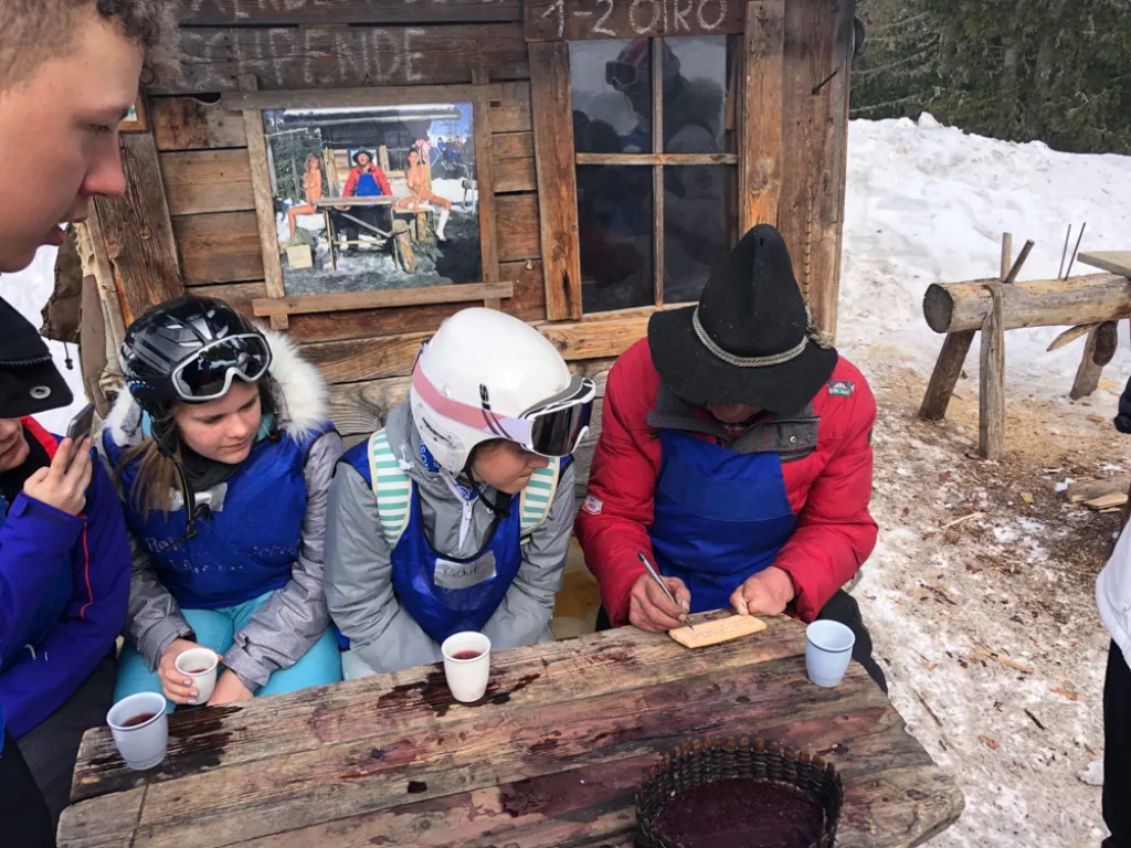 Jugendliche sitzen mit Bechern an einem Tisch im Schnee.